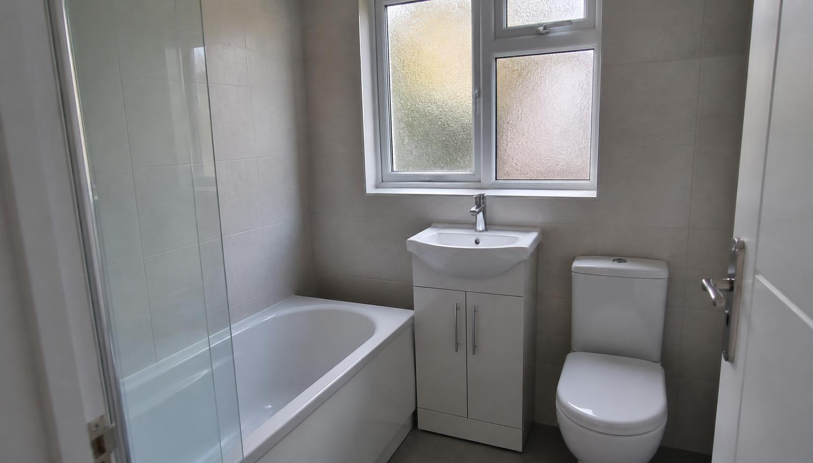 Newly fitted family bathroom with bath, shower screen and basin unit